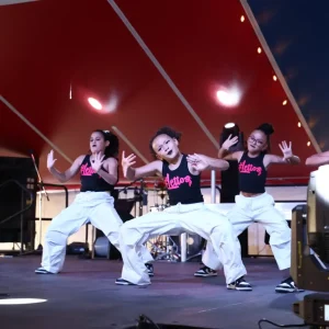 Dancers performing on stage under red lights.