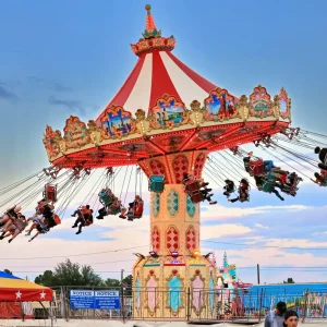 Carnival swing ride at sunset, colorful sky.